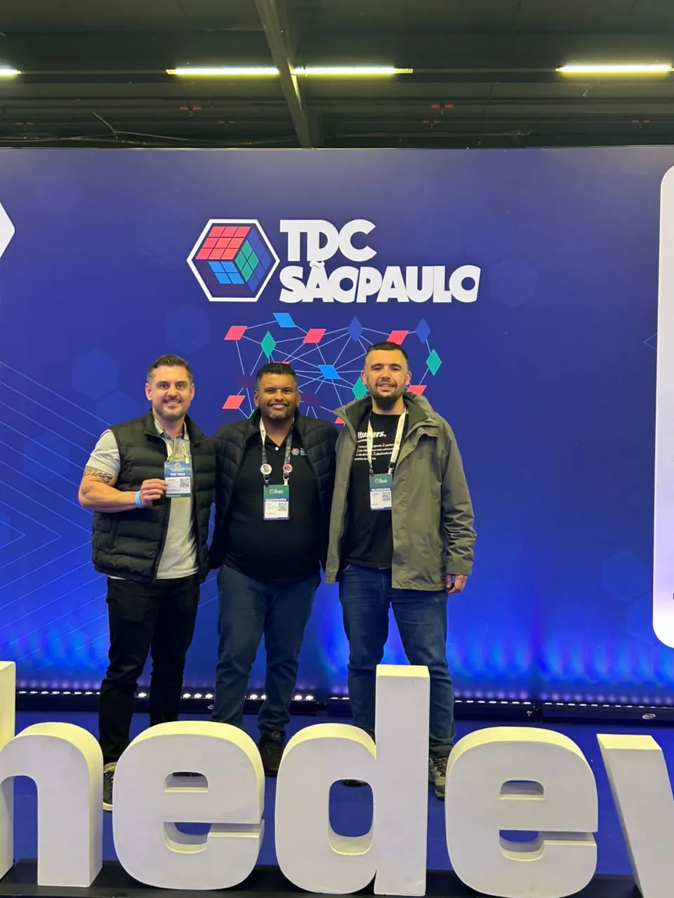 Três amigos diante do painel do TDC São Paulo 2026